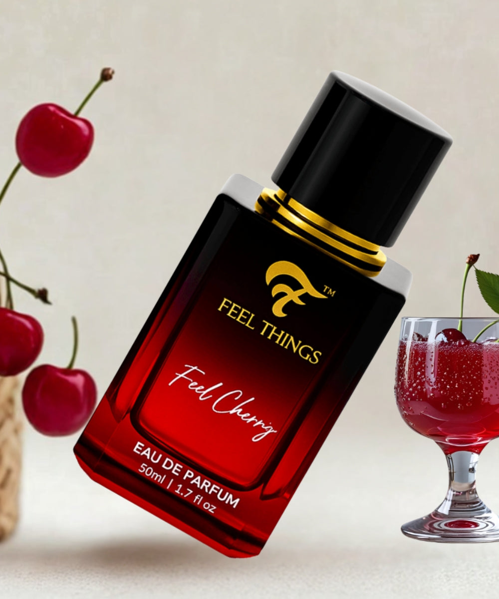 Red and black perfume bottle labeled 'Feel Things Feel Cherry' with cherries and a glass in the background.