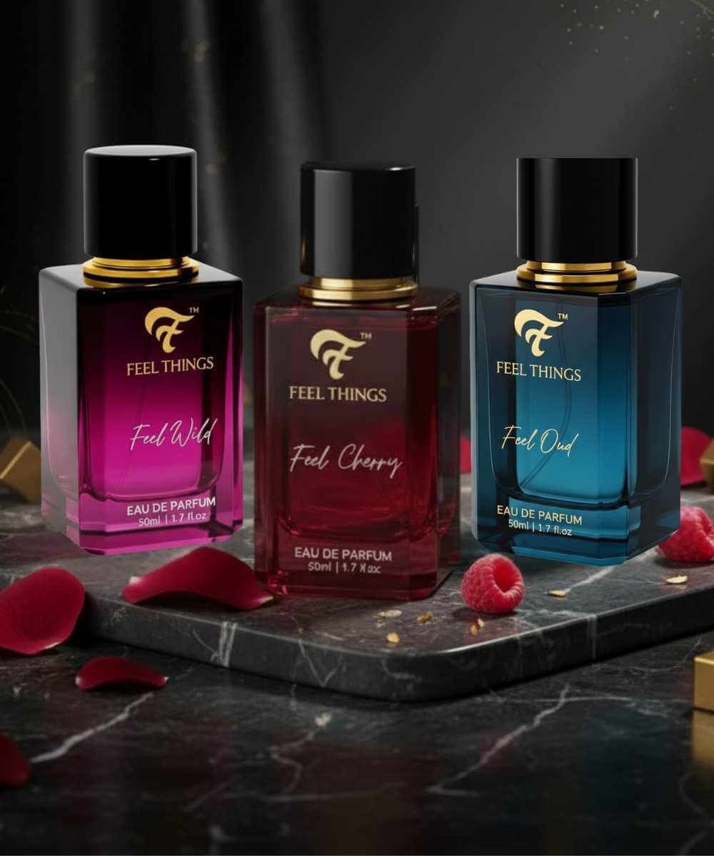 Trio Perfume bottles of 'Feel Things' perfume on a dark surface with flowers.